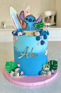 a blue and pink birthday cake with an image of stitching lillies on it