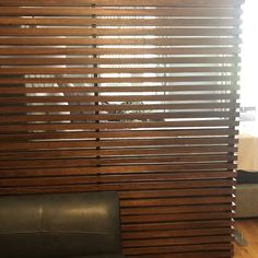 a wooden slatted wall in a living room next to a black leather chair