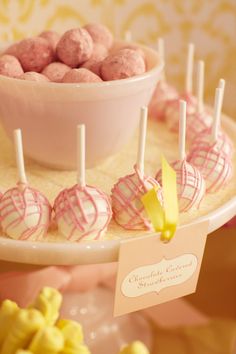 pink and yellow desserts are displayed on a white plate with candy sticks in the middle