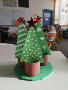 three paper christmas trees sitting on top of a table in front of some children's desk