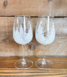 two wine glasses sitting on top of a wooden table