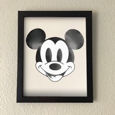 a mickey mouse face drawn in black and white on a wall above a framed photo