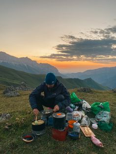 a man sitting on top of a grass covered field next to a bag filled with food