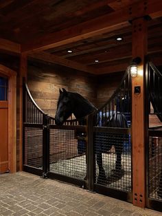 a horse is standing behind a fence in an enclosed area with lights on the ceiling