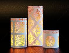 three lit candles sitting next to each other on top of a wooden table in front of a black background