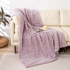 a couch with a blanket on top of it next to a coffee cup and potted plant