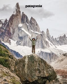 a person standing on top of a rock with their arms in the air and mountains in the background