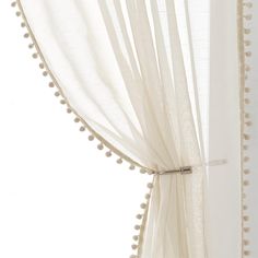 a white curtain with pom - poms hanging from it's side