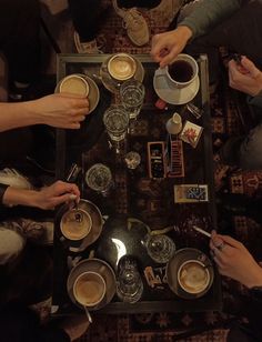 four people sitting at a table with cups and saucers