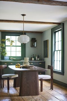 a kitchen with green walls and wooden flooring has a round dining table surrounded by chairs