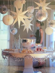 a table topped with lots of silverware and paper stars hanging from it's ceiling