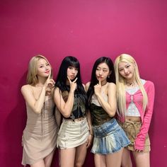 four girls standing in front of a pink wall with their hands on their hipss