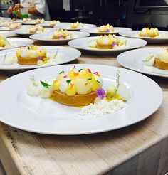 several white plates topped with desserts sitting on top of a wooden table in a kitchen