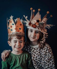 two children with crowns on their heads posing for a photo in front of a blue background