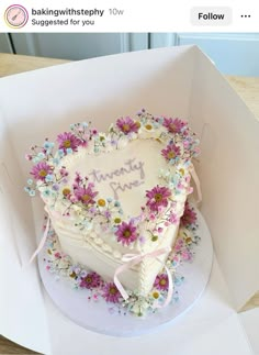 a heart shaped cake in a white box with pink and blue flowers on it that says thank you