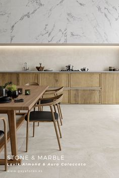 a kitchen with marble walls and flooring next to a dining room table surrounded by chairs