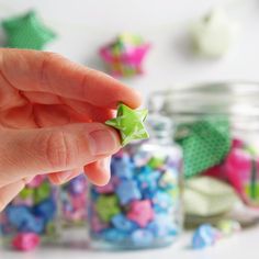 a hand is holding a green star shaped object in front of some colorful candies