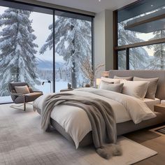 a large bed sitting in the middle of a bedroom next to a window filled with snow covered trees