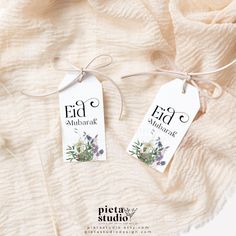 two tags tied together on a blanket with the words eid mubarak and floral designs