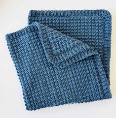 a blue knitted scarf laying on top of a white table