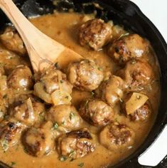 meatballs and gravy in a skillet with a wooden spoon on the side