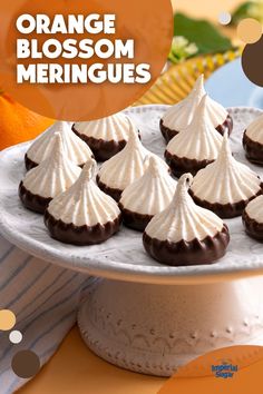 orange blossom meringues on a white plate with an orange in the background and text overlay that reads orange blossom meringues