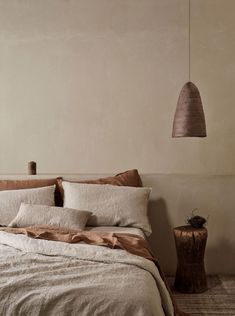 a bed with two lamps hanging from the ceiling and pillows on the bed in front of it