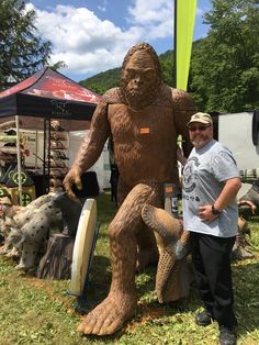 a man standing next to a bigfoot statue