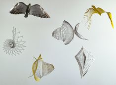 several metal birds hanging from strings on a wall