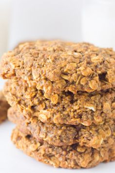 three oatmeal cookies stacked on top of each other next to a glass of milk