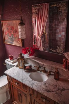 a bathroom with red walls and marble counter tops