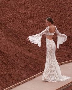 a woman in a white dress is standing on a brick walkway with her arms outstretched