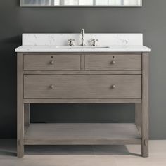 a bathroom vanity with two drawers and a mirror on the wall above it, in front of a gray wall