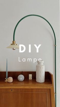 a lamp on top of a wooden cabinet next to a white vase and other items