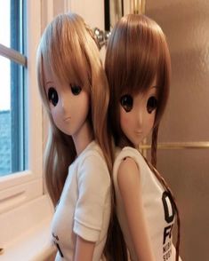 two dolls sitting next to each other in front of a window