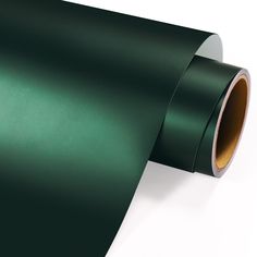 a roll of dark green metallic paper on a white background with gold foil in the corner