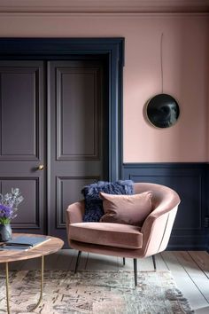 a living room with pink walls and blue trim on the door, two chairs and a coffee table