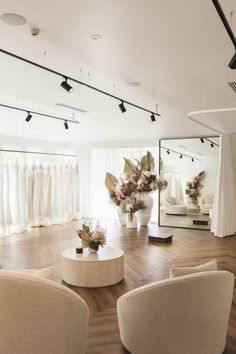 a room with white furniture and flowers in vases