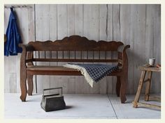 an old wooden bench with a blanket on it next to a small table and stool