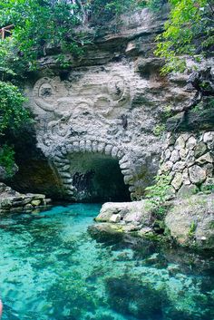 the water is crystal blue and clear in this cave with a carved face on it