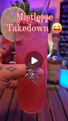 someone holding up a pink cocktail with a ring on it's thumb and the words mistlet toe takedown