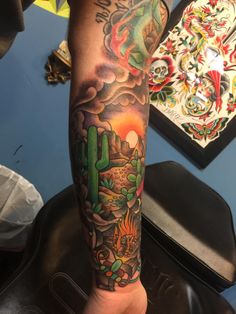 a man's arm with tattoos on it and a cactus in the desert behind him