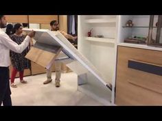 two men and one woman unpacking furniture in a room with open shelving