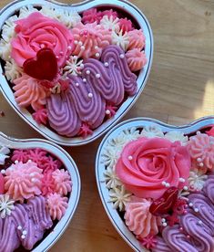 three heart shaped cupcakes with pink and purple frosting in them on a table