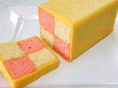 two pieces of yellow and pink cake sitting on top of a white plate next to each other