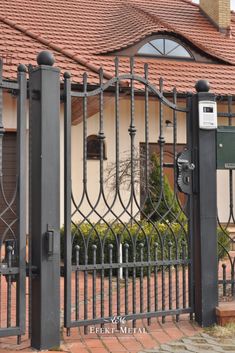 an iron gate is shown in front of a brick house with a red tiled roof