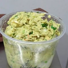 a plastic container filled with food sitting on top of a metal counter next to a person's hand