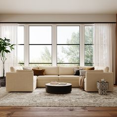 a modern living room with large windows and beige couches, coffee table, vases and potted plant