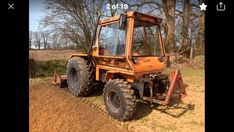 an orange tractor is parked in the dirt