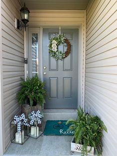 the front door is decorated for christmas with wreaths and potted plants